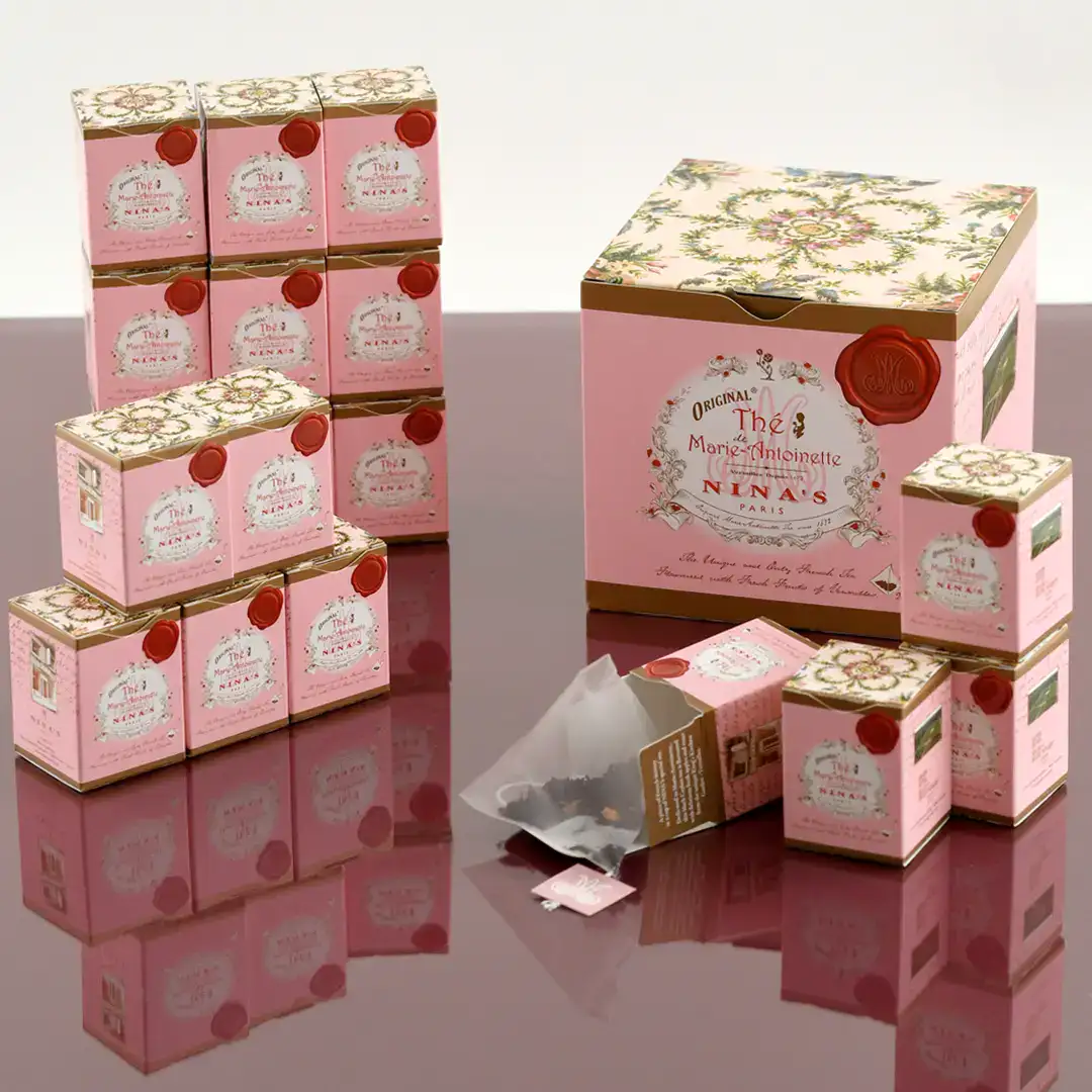 Confezioni di tè rosa e oro con packaging elegante e dettagli floreali.