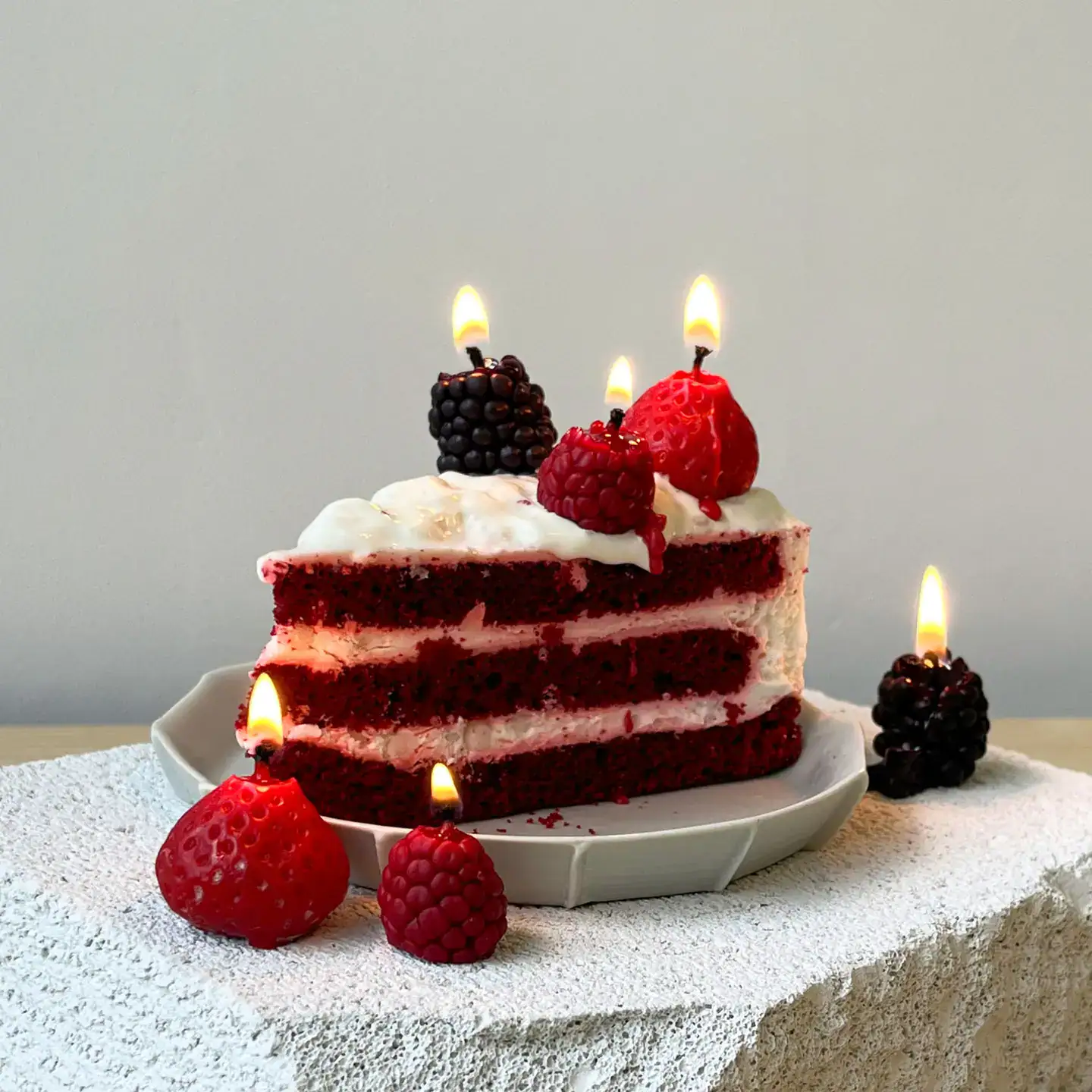 Torta rossa con frutti di bosco e candeline accese, decorazione elegante.