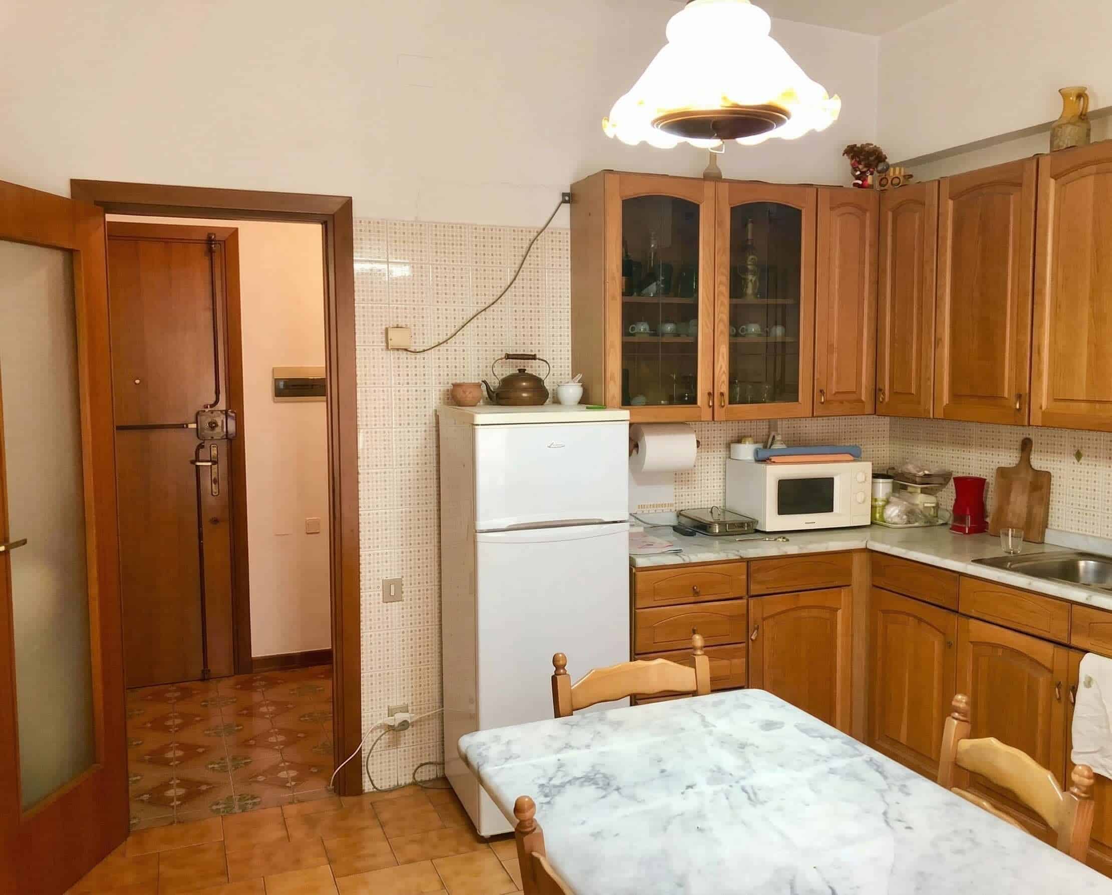 prima-dopo-cucina-legno.jpg Lavagna bianca moderna in cucina con mobili in legno e elettrodomestici essenziali.